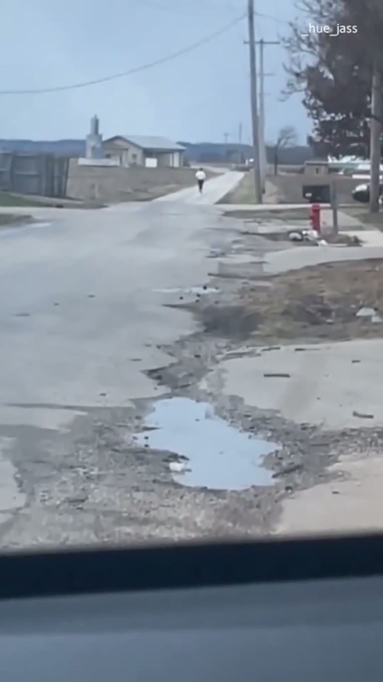 Jogger Appears Frozen in Place on Quiet Road in Odd Clip