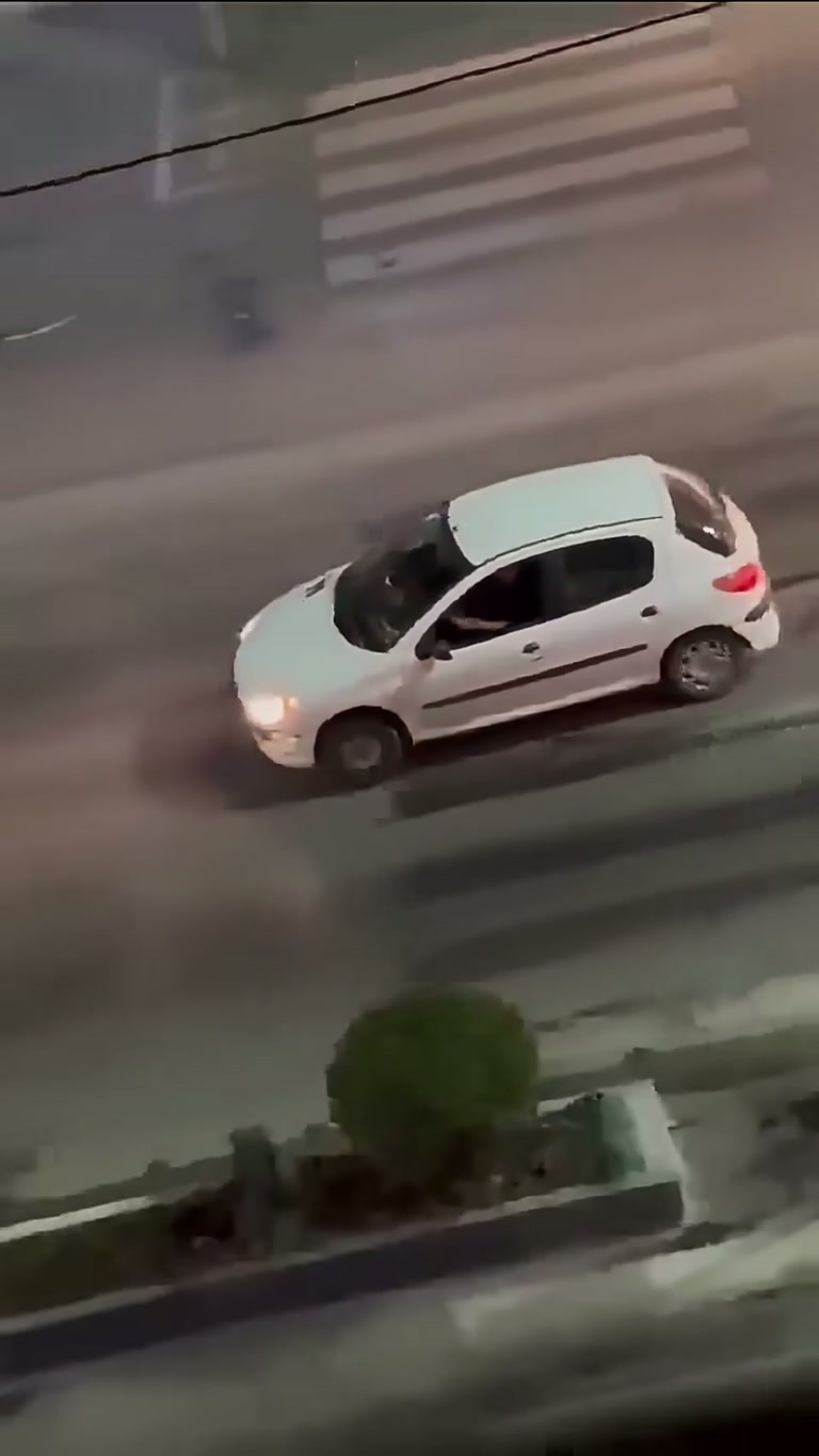 Night Street Chaos: White Car, Blue Truck, and a Crowd