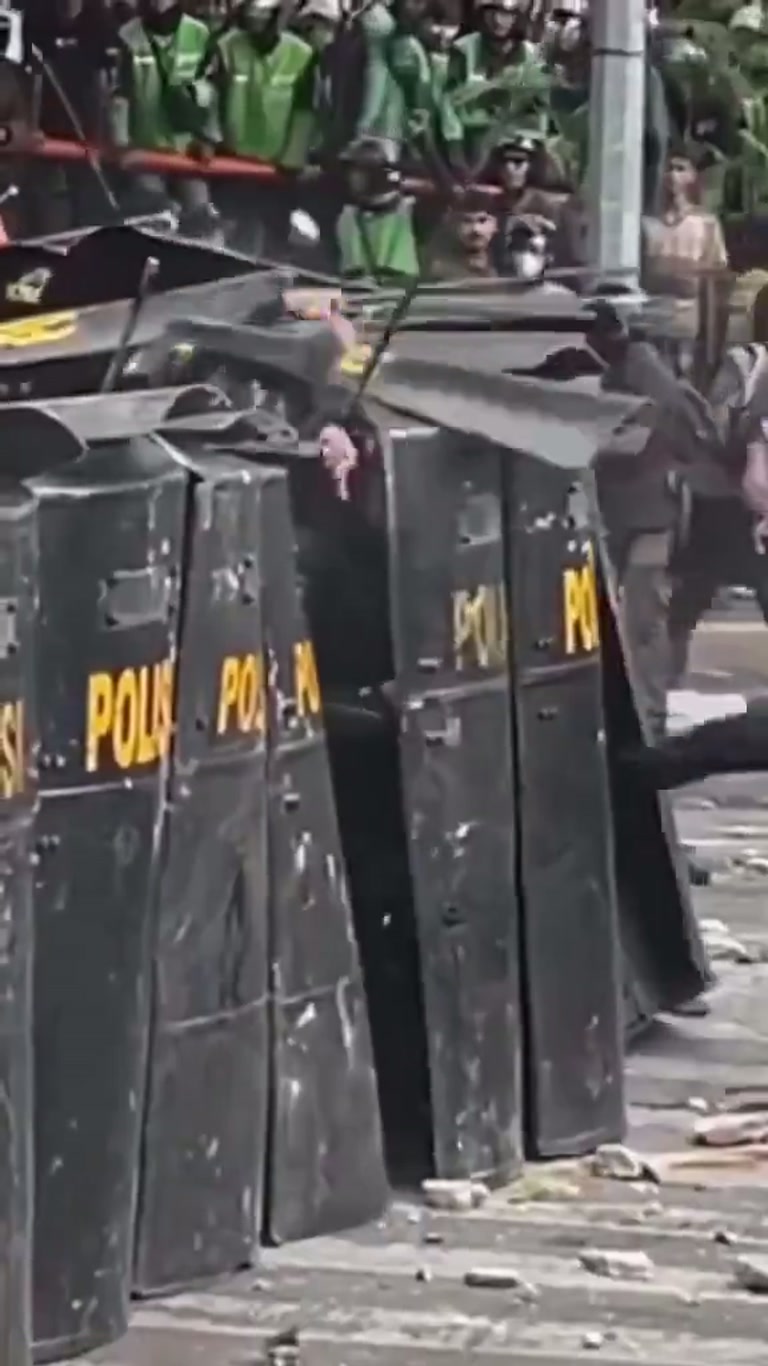 Pink Shirt and Police Shields: Chaos on a Debris-Strewn Street