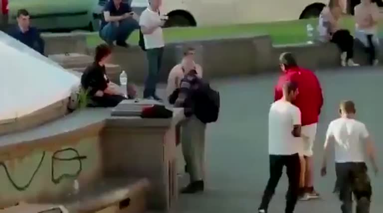 Tension in a Public Square as a Shirtless Man Faces a Group