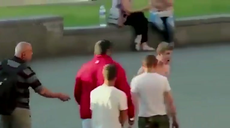 Tension in a Public Square as a Shirtless Man Faces a Group