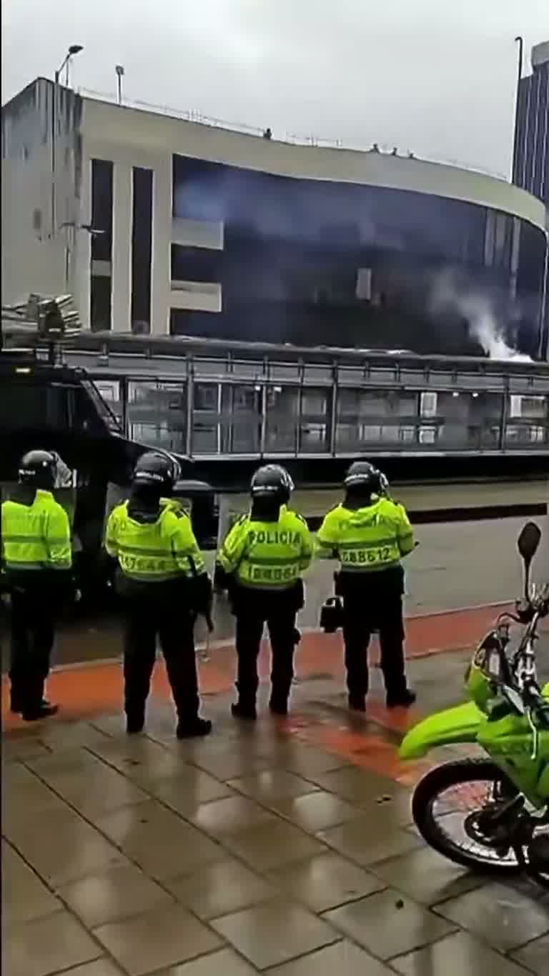A Wall of Green Helmets Waits Quietly on a Soaked Avenue
