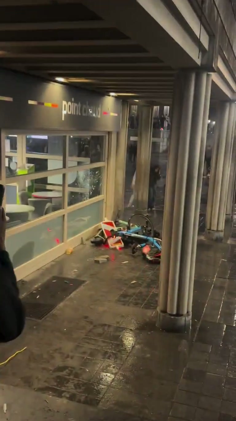 A Hooded Figure, a Wet Sidewalk, and One Device Left Behind