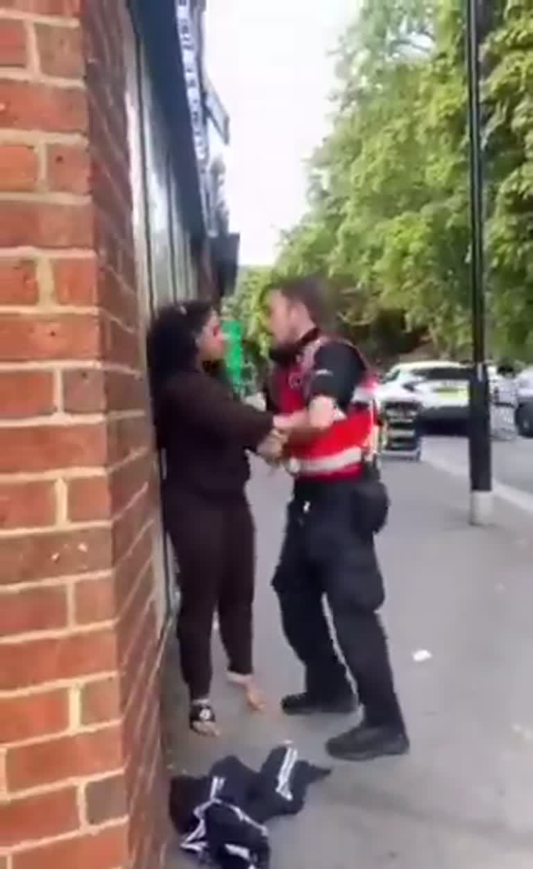 Pavement Standoff: Store Guard and Woman Wait as Police Pull Up