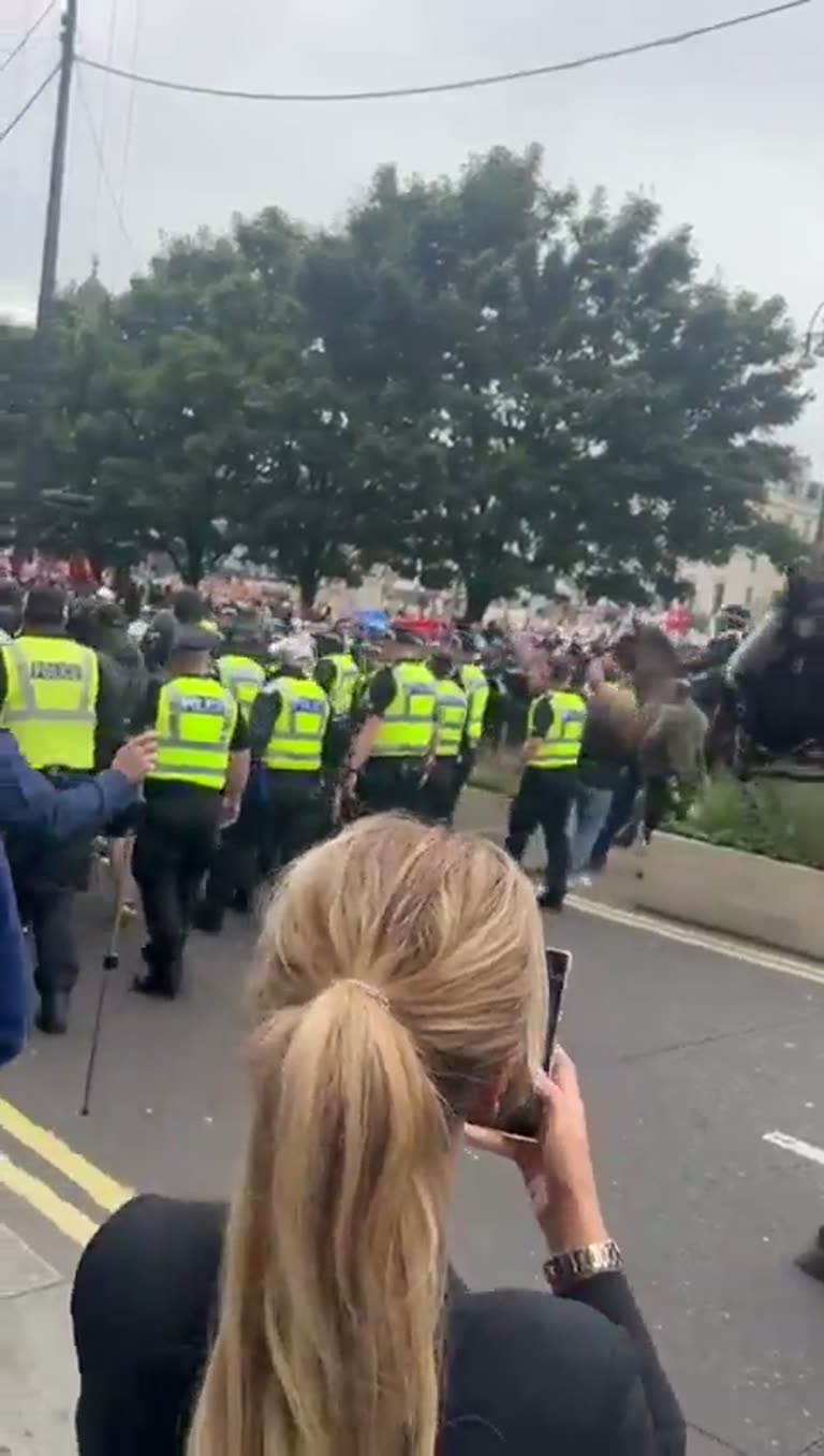 Police horses and masked men move through George Square