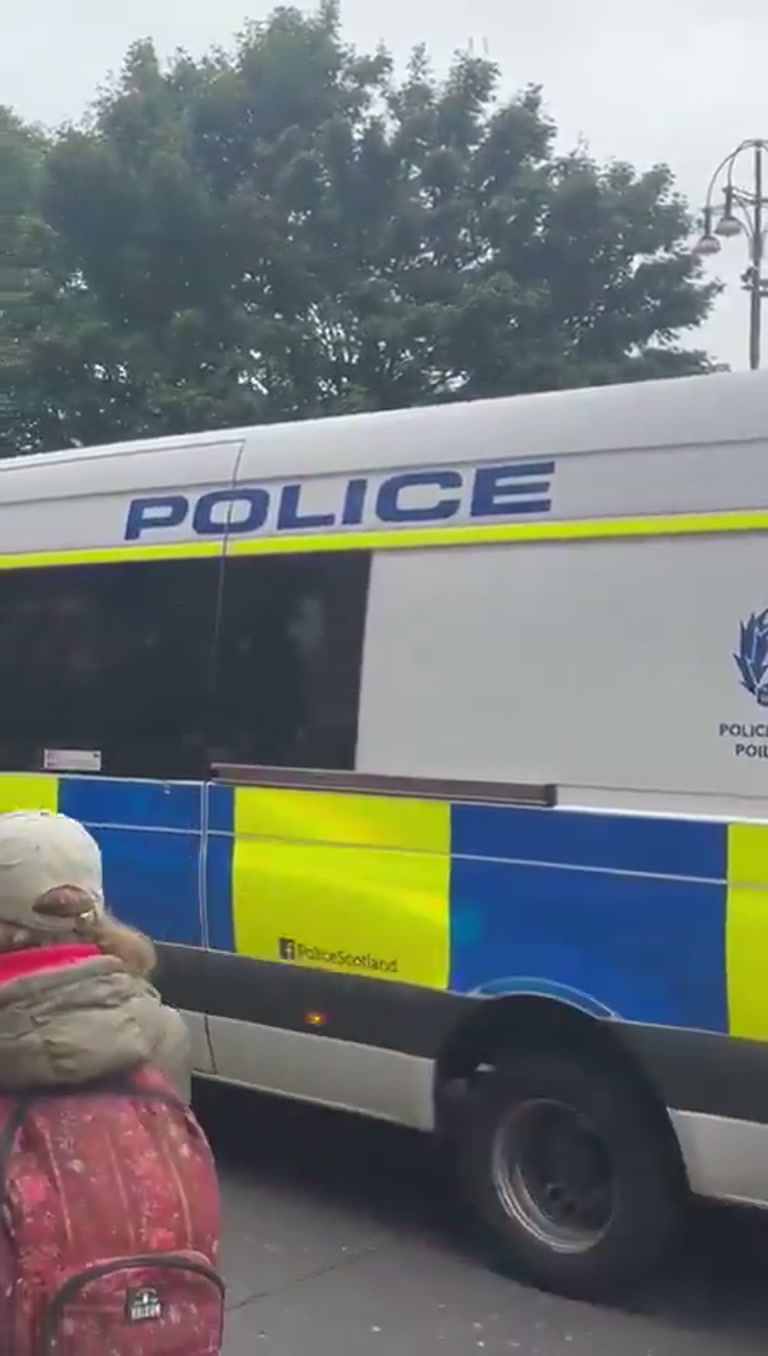 Police horses and masked men move through George Square